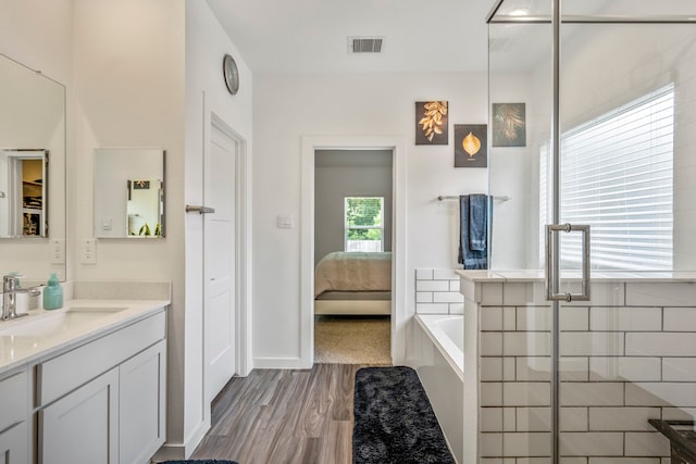 bathroom with wood-type flooring, vanity, and shower with separate bathtub