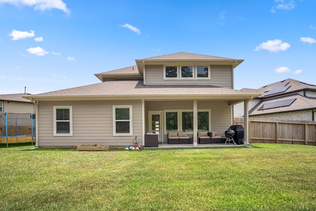 back of house featuring a patio area, a lawn, outdoor lounge area, and a trampoline