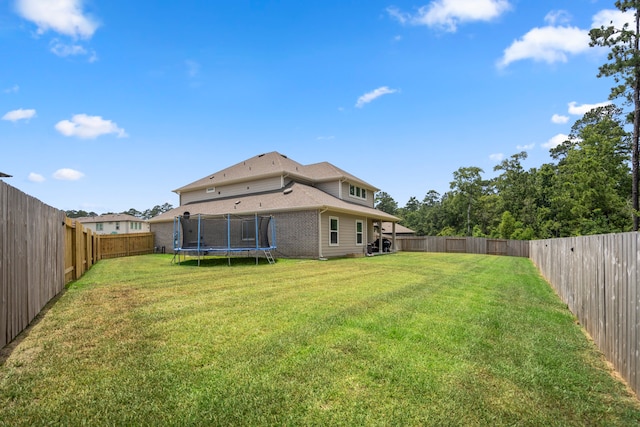 rear view of house featuring a lawn and a trampoline