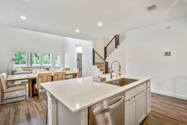 kitchen featuring white cabinetry, hardwood / wood-style floors, sink, stainless steel dishwasher, and a kitchen island with sink