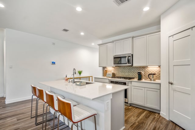 kitchen featuring a kitchen island with sink, appliances with stainless steel finishes, dark hardwood / wood-style floors, and sink