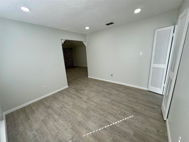 spare room featuring a textured ceiling and hardwood / wood-style flooring