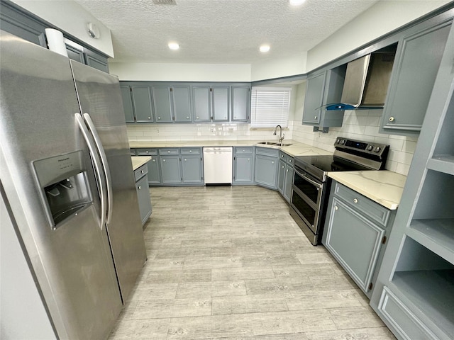 kitchen featuring decorative backsplash, appliances with stainless steel finishes, wall chimney exhaust hood, and a textured ceiling