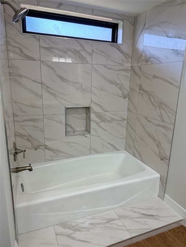 bathroom with hardwood / wood-style flooring and tiled shower / bath