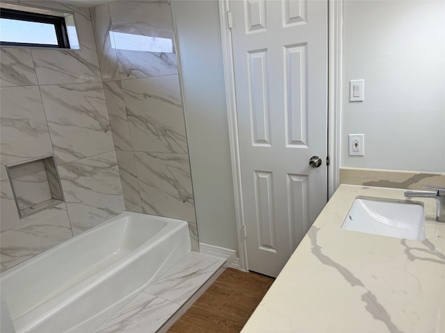 bathroom featuring hardwood / wood-style floors, vanity, and tiled shower / bath