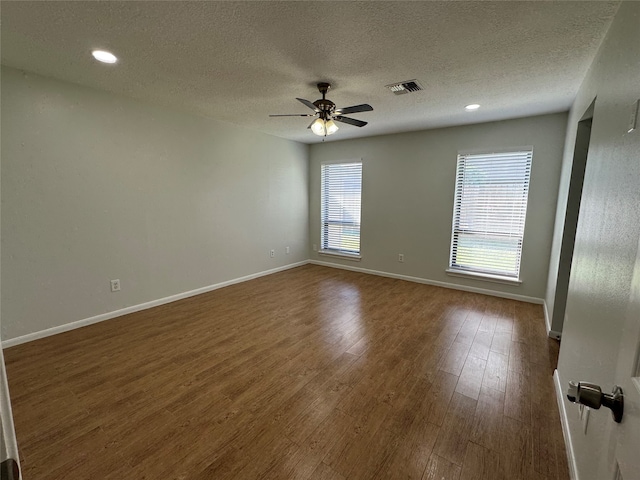 spare room featuring dark wood-type flooring, ceiling fan, and a textured ceiling