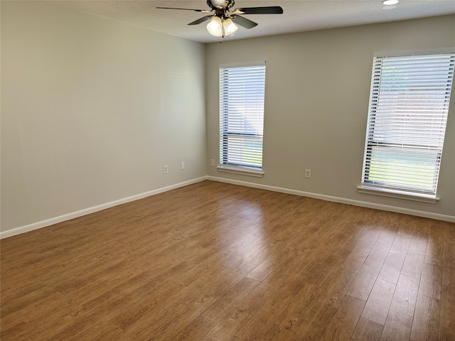 empty room with ceiling fan, wood-type flooring, a healthy amount of sunlight, and a textured ceiling