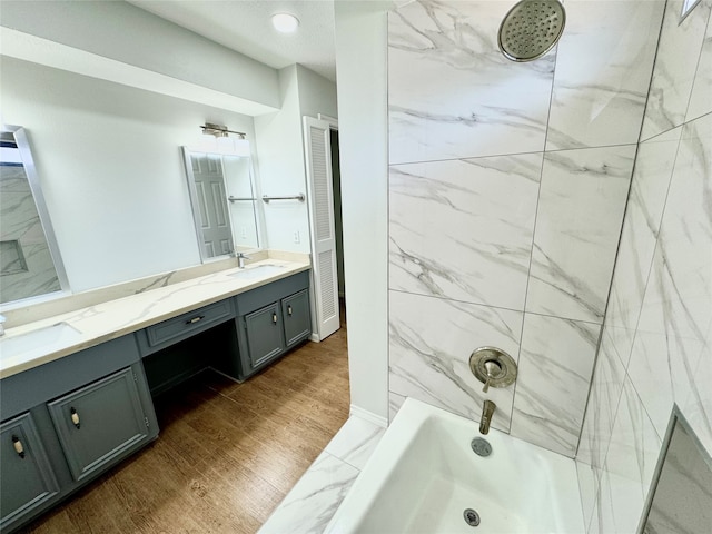 bathroom with vanity, hardwood / wood-style flooring, and tiled shower / bath