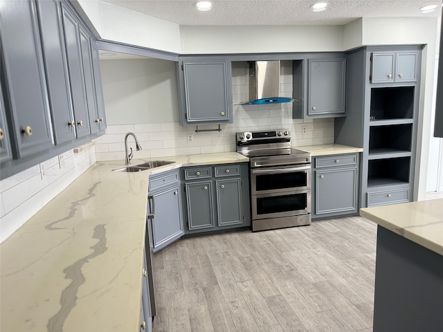 kitchen featuring range with two ovens, a textured ceiling, sink, gray cabinets, and wall chimney range hood