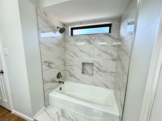 bathroom with hardwood / wood-style floors, a textured ceiling, and tiled shower / bath combo