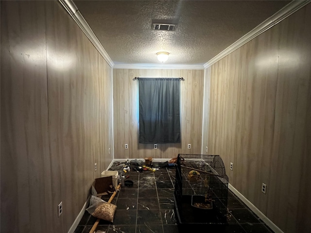 miscellaneous room with tile patterned flooring, wooden walls, a textured ceiling, and crown molding