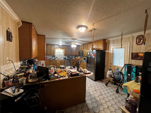 kitchen with kitchen peninsula, appliances with stainless steel finishes, ceiling fan, a textured ceiling, and crown molding