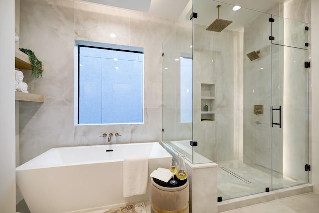 bathroom with tile walls and independent shower and bath