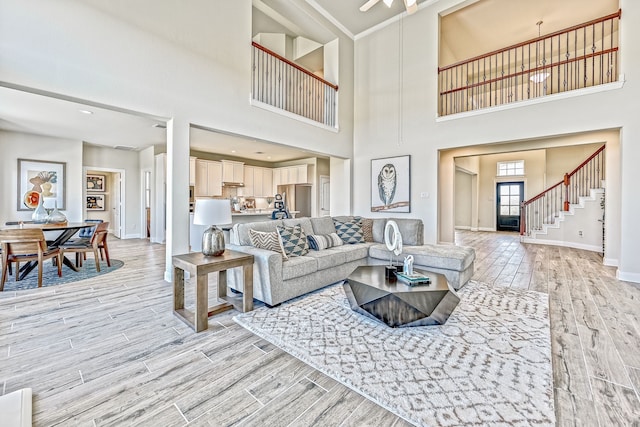 living room featuring a high ceiling, ceiling fan, and light hardwood / wood-style floors