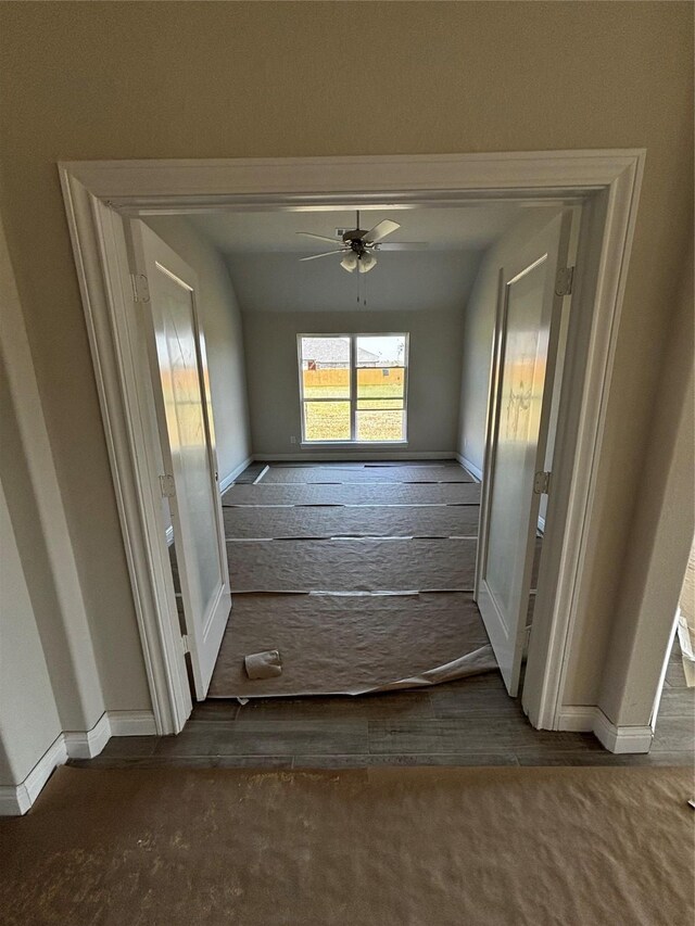 corridor with dark carpet and vaulted ceiling