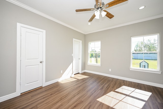 spare room featuring dark wood-type flooring, ceiling fan, crown molding, and plenty of natural light