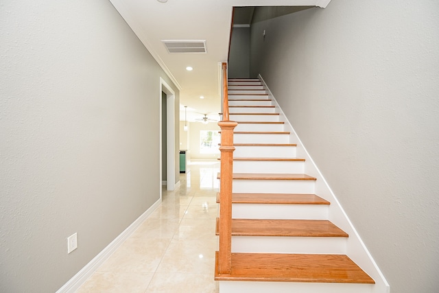 stairs with tile patterned floors and crown molding