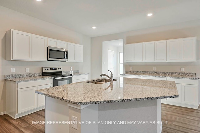 kitchen with white cabinetry, appliances with stainless steel finishes, a center island with sink, and light hardwood / wood-style flooring