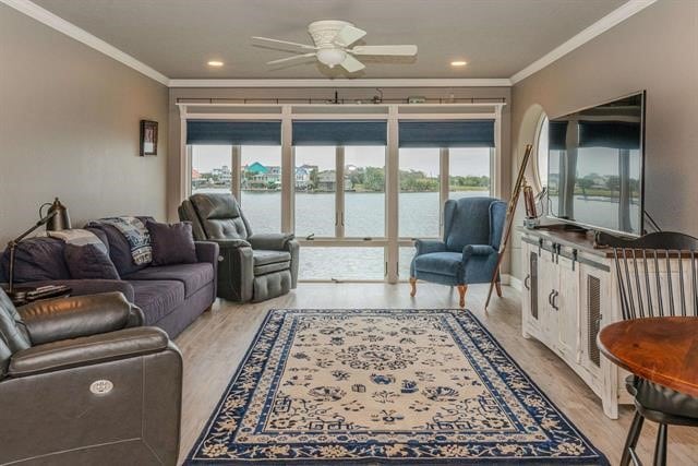 living room with ornamental molding, light wood-type flooring, and ceiling fan