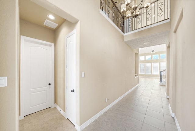 hall with light tile patterned floors and an inviting chandelier