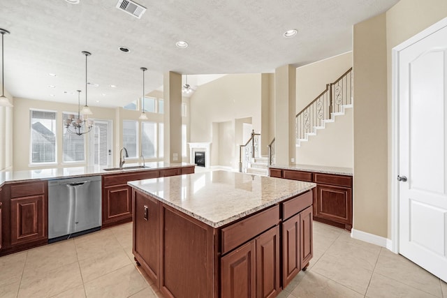 kitchen featuring a center island, sink, hanging light fixtures, stainless steel dishwasher, and a textured ceiling