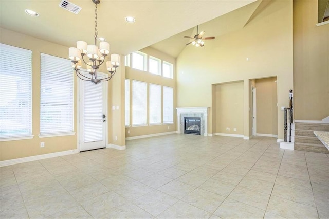 unfurnished living room with a wealth of natural light, light tile patterned floors, high vaulted ceiling, and ceiling fan with notable chandelier