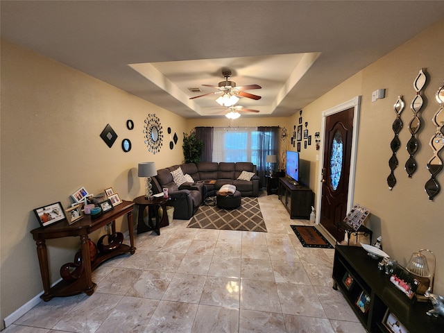 living room with a tray ceiling and ceiling fan