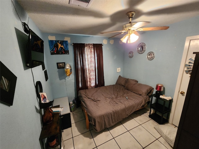 bedroom featuring ceiling fan, a textured ceiling, and light tile patterned floors