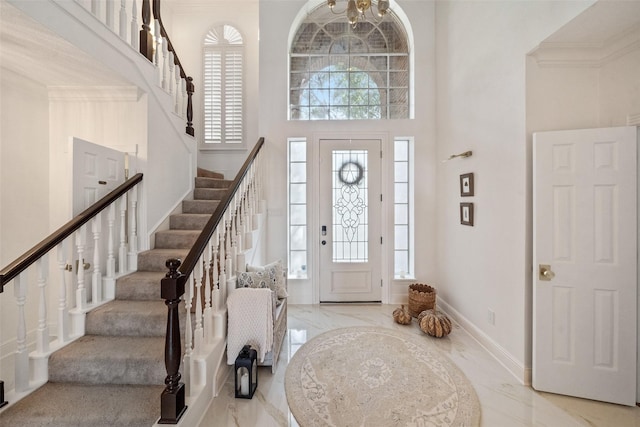 foyer entrance featuring a towering ceiling and ornamental molding