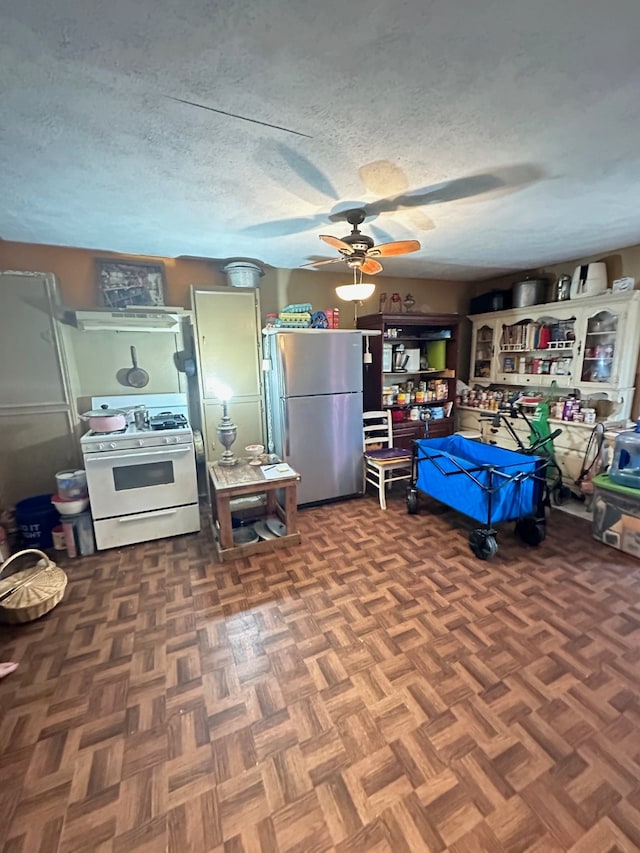 kitchen with stainless steel refrigerator, ceiling fan, a textured ceiling, white range with gas stovetop, and parquet floors