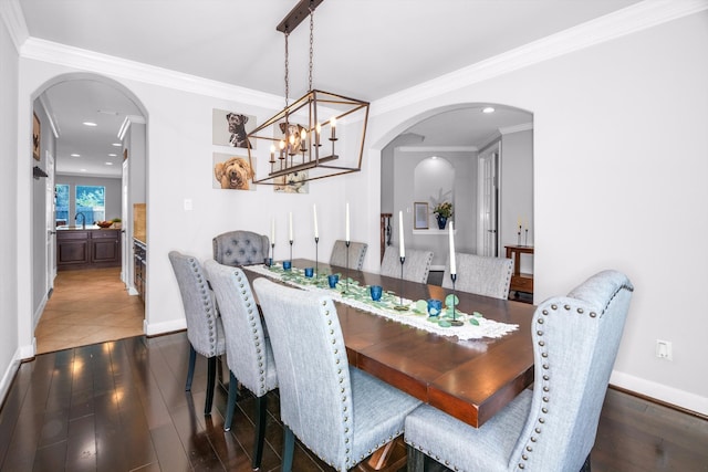 dining area with dark hardwood / wood-style floors, ornamental molding, sink, and a chandelier