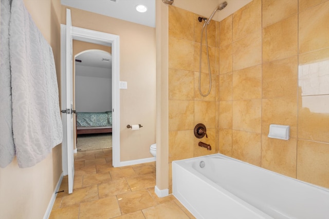 bathroom with toilet and tiled shower / bath