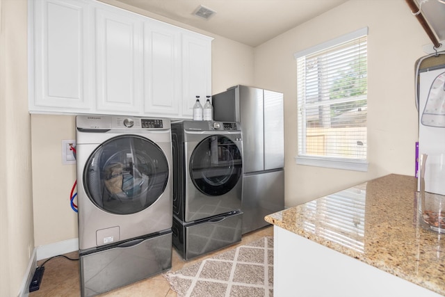 laundry area featuring cabinets, independent washer and dryer, and light tile patterned floors