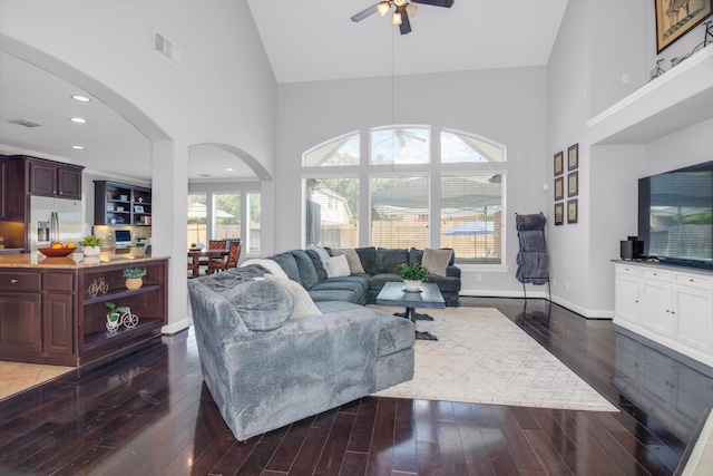 living room featuring a healthy amount of sunlight, ceiling fan, high vaulted ceiling, and dark wood-type flooring