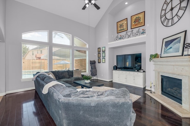 living room featuring dark hardwood / wood-style floors, ceiling fan, a fireplace, and high vaulted ceiling