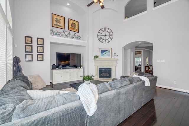 living room featuring ceiling fan, dark hardwood / wood-style flooring, and a towering ceiling