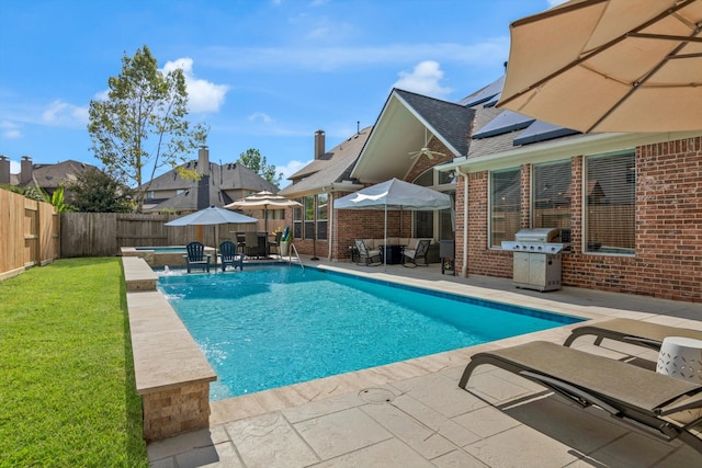 view of pool with pool water feature, area for grilling, a patio area, and a lawn