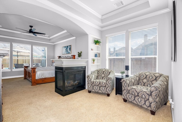 interior space with multiple windows, light colored carpet, a raised ceiling, and ceiling fan