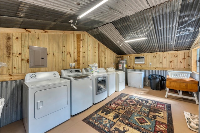 laundry room featuring wood walls, electric panel, and washing machine and clothes dryer