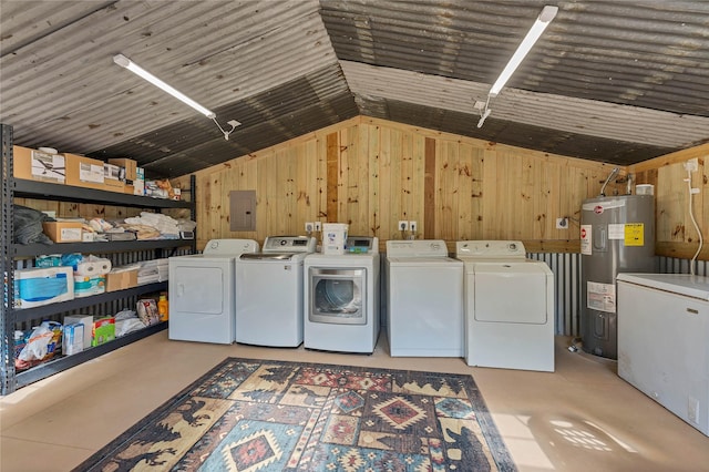 laundry room featuring water heater, independent washer and dryer, wood walls, and electric panel