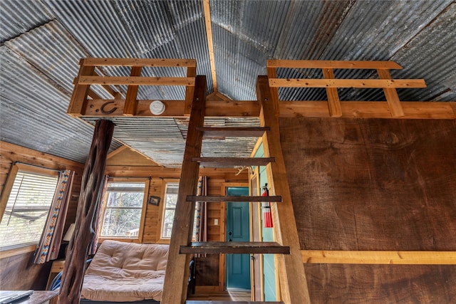 unfurnished bedroom with lofted ceiling and wooden walls