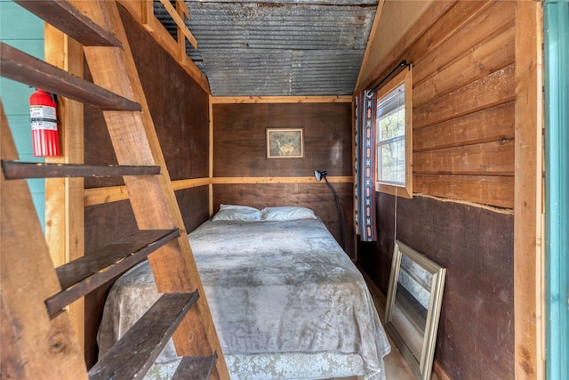 bedroom with vaulted ceiling and wooden walls