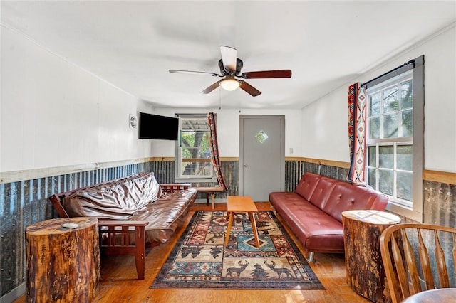 living room with ceiling fan, a healthy amount of sunlight, hardwood / wood-style floors, and wooden walls