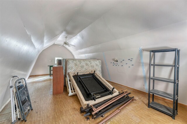 exercise room with vaulted ceiling, ceiling fan, and light hardwood / wood-style flooring