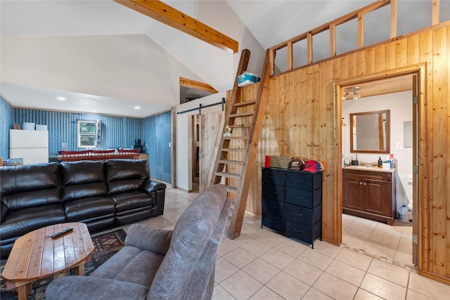 living room featuring light tile patterned flooring, wood walls, a barn door, and vaulted ceiling