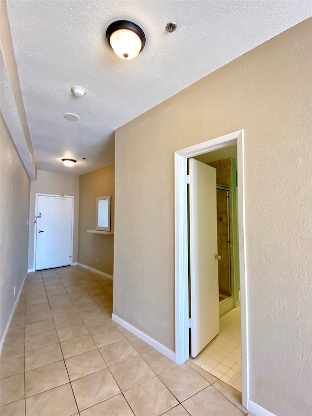 corridor with light tile patterned flooring and a textured ceiling