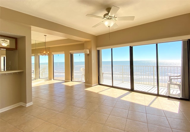 unfurnished room featuring ceiling fan with notable chandelier, light tile patterned flooring, and a water view