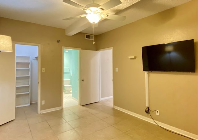 unfurnished bedroom featuring ensuite bath, ceiling fan, a spacious closet, a closet, and light tile patterned flooring