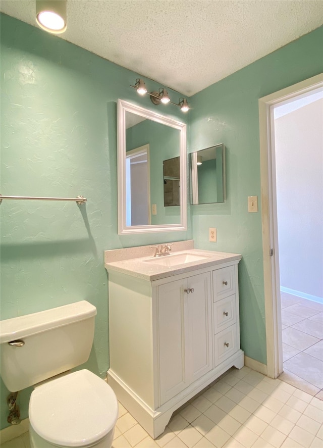 bathroom featuring tile patterned flooring, vanity, toilet, and a textured ceiling