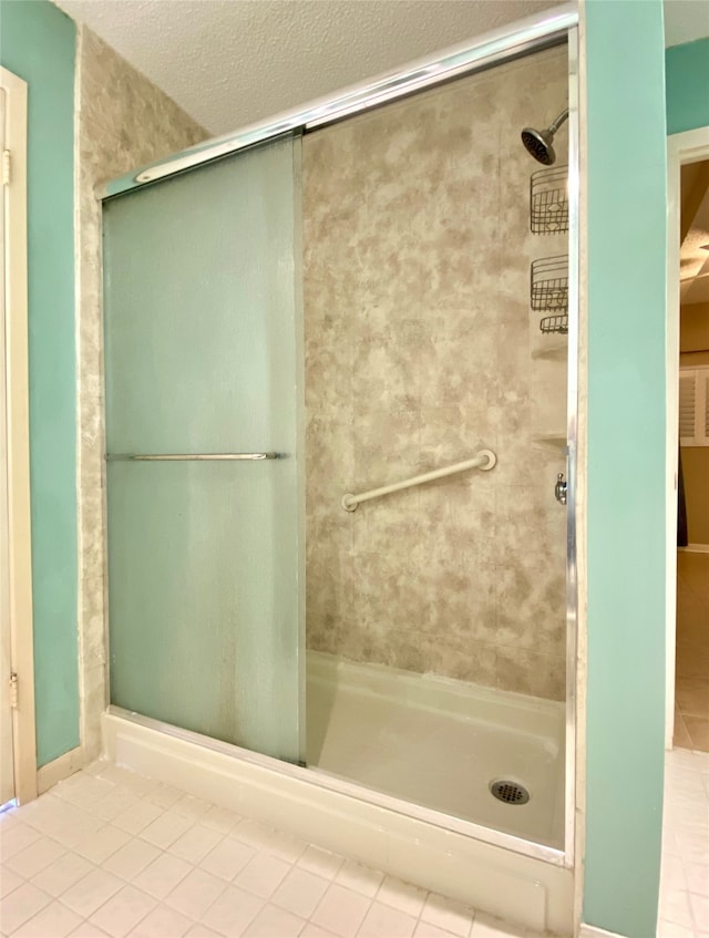 bathroom featuring tile patterned flooring, a textured ceiling, and an enclosed shower